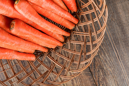 Carrot in basket on a wooden surfaceの写真素材