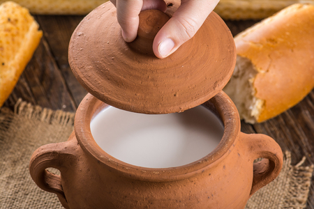 Clay pot with milk and baguette on a wooden tableの写真素材