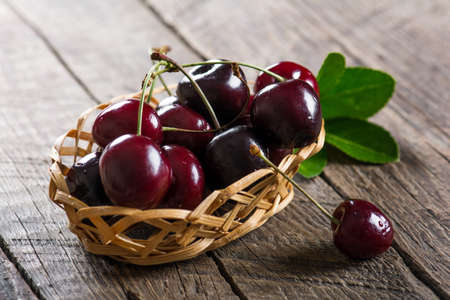 Cherry on a wooden table in a wickerの写真素材