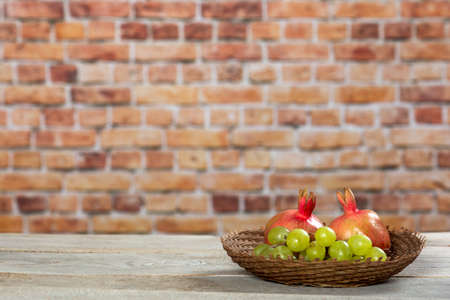 Pomegranates and grapes in a wicker bowlの写真素材