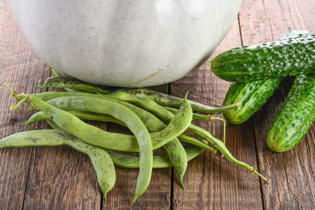 Green beans pods, cucumbers and pumpkin on wooden surfaceの写真素材