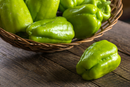 Green bell pepper in wicker basketの写真素材