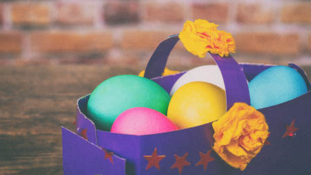 Colorful festive easter eggs in paper basket. Toned under the old film, added grain and noiseの写真素材