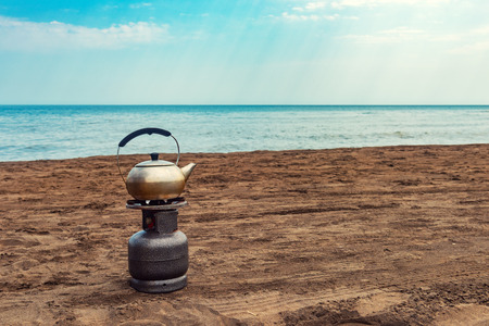 Boiling tea on a gas bottle by the seaの写真素材