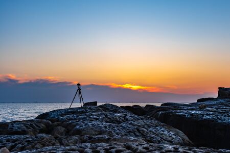 Camera on a tripod shoots a colorful sunrise at sea