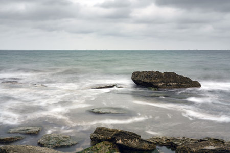 Long exposure, rocky sea beach at cloudy weather