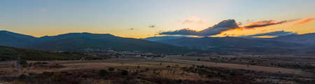 Colorful sunset over the mountains. Wide panorama overlooking the village and farm fieldsの写真素材
