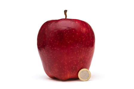 Big red apple on white background, size comparison with a coinの写真素材
