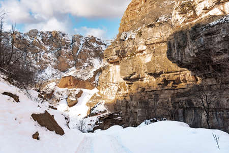 Narrow snowy road in a mountain gorgeの写真素材