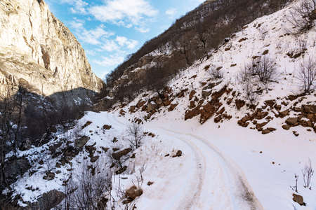 Narrow snowy road in a mountain gorgeの写真素材