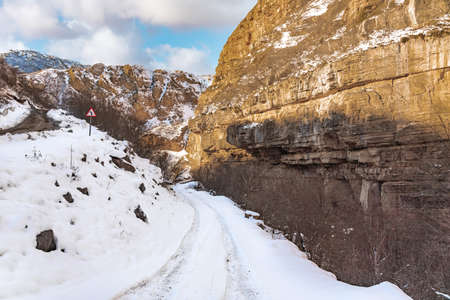 Narrow snowy road in a mountain gorgeの写真素材
