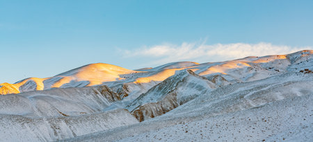 Snow covered mountain peak lit by the rising sunの写真素材