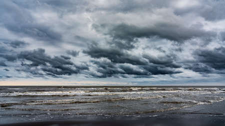 Waves on the sea beach on a cloudy rainy dayの写真素材