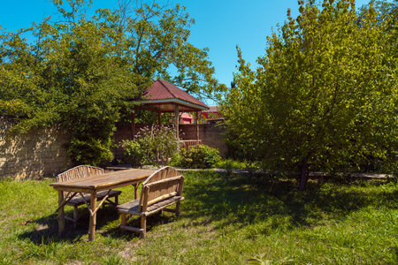 Wooden handmade table and benches on the grass in the garden of country houseの写真素材