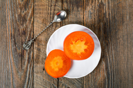 Juicy tropical persimmon fruit on plateの写真素材