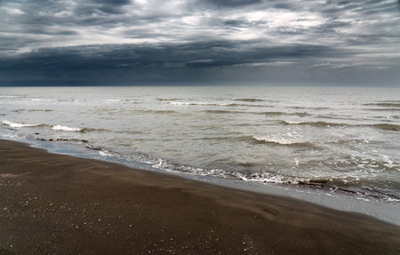 Sandy sea shore in cloudy weather with thundercloudsの写真素材