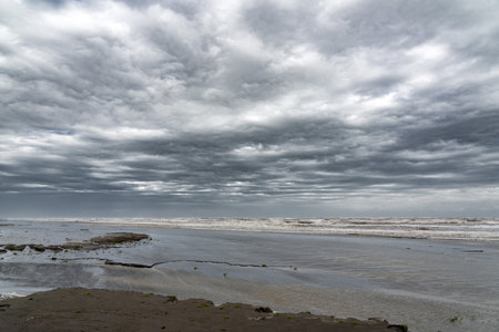 Sandy sea shore in cloudy weather with thundercloudsの写真素材
