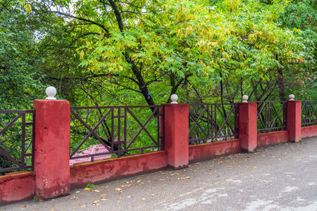 Stone fence with metal lattice and green treeの写真素材