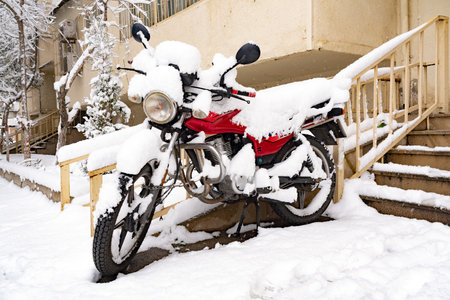 Motorcycle covered with snow in the yard of the house in winterの写真素材