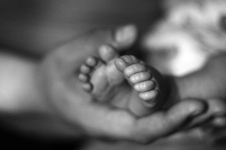 Newborn baby's feet in father's hand.