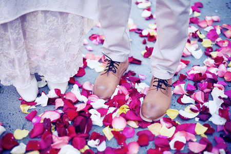 Bride and groom standing amongst rose petalsの写真素材