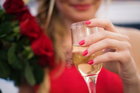 Young woman holding a glass of champagne and a roses bouquetの写真素材