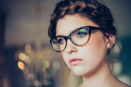Portrait of pretty young woman wearing glasses. Professional make-up and hairstyle. Perfect skin. Fashion photo.の写真素材