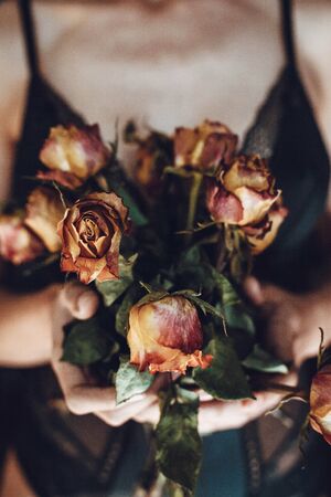 Woman holding bouquet of dried roses. Caducity of beauty concept.の写真素材