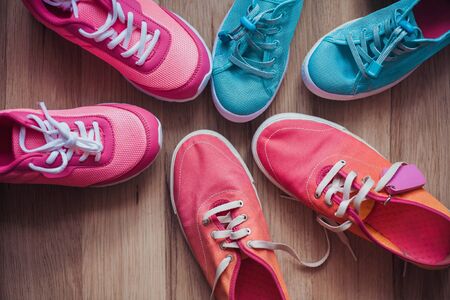 Three pairs of colorful sneakers on a wooden background.の素材 [FY310131578554]