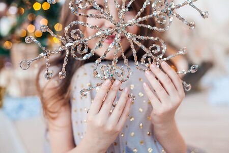 Little girl holding in hands sparkling Christmas snowflake decoration.の写真素材