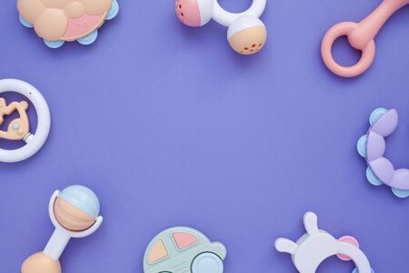 Flat lay composition with baby rattles set in pastel colors and space for text on lilac background.の写真素材