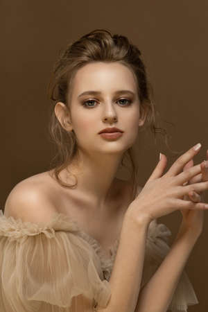 Beauty portrait of young caucasian model with bare shoulders. Trendy fashion studio shot in beige tones.の写真素材