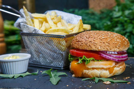 Black burger on a wooden background with potatoes and sauceの写真素材