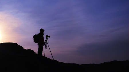 Silhouette of a photographer at sunrise on the mountains in the early morningの写真素材