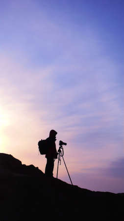 Silhouette of a photographer on the mountains at sunriseの写真素材