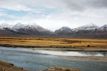 Landscape of snow mountains and stream in Tibetの写真素材