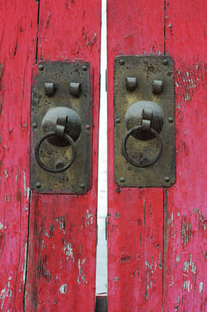 Copper doorknob or knockers on a red gateの写真素材