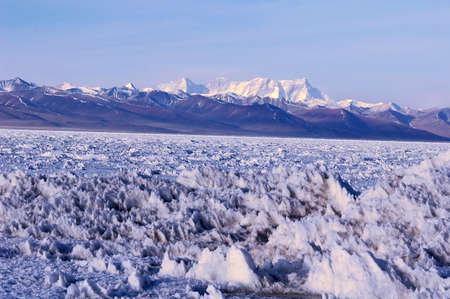 Landscape of snow-capped mountains and frozen lake in winter