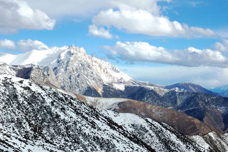 Landscape of snow-capped mountains and cloudy skies in winterの写真素材