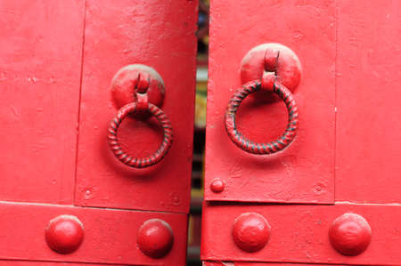 Closeup view of red doors with iron doorknobsの写真素材