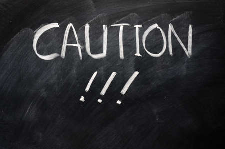 Caution written on blackboard with exclamation marks