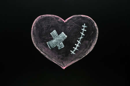 Broken heart drawn with chalk on a blackboardの写真素材