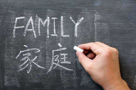 Family - word written on a blackboard with a Chinese translationの写真素材