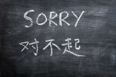 Sorry - word written on a smudged blackboard with a Chinese translationの写真素材