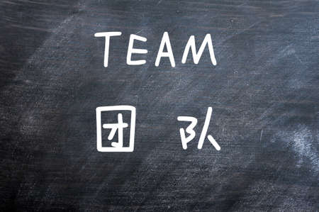 Team - word written on a smudged blackboard with a Chinese translationの写真素材