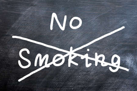 No smoking written on a smudged blackboard with a crossの写真素材