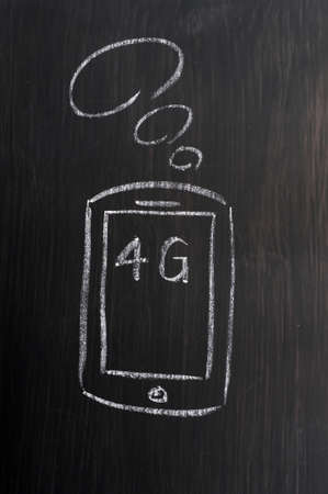 Mobile phone and 4G concept drawn with white chalk on a wooden blackboardの写真素材