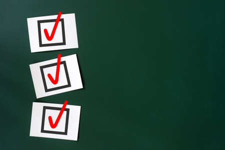 Check box with red tick on a green chalkboard, with copy space for textの写真素材