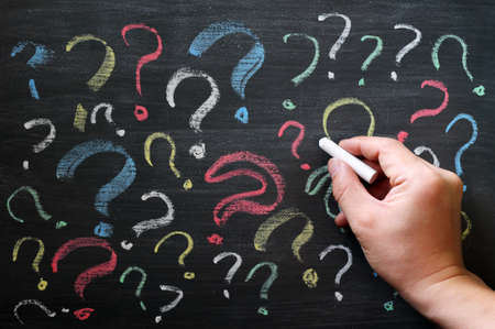 Question marks on chalkboard. Decision, confusion, FAQ or other concept. Hand writing with chalk on...