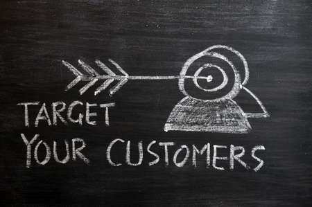 'Target your customers' concept drawn with white chalk on a blackboardの写真素材